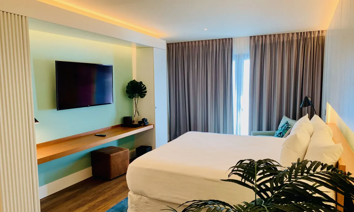 Executive Suite City View king bed facing wall-mounted TV at Holland House Beach Hotel.