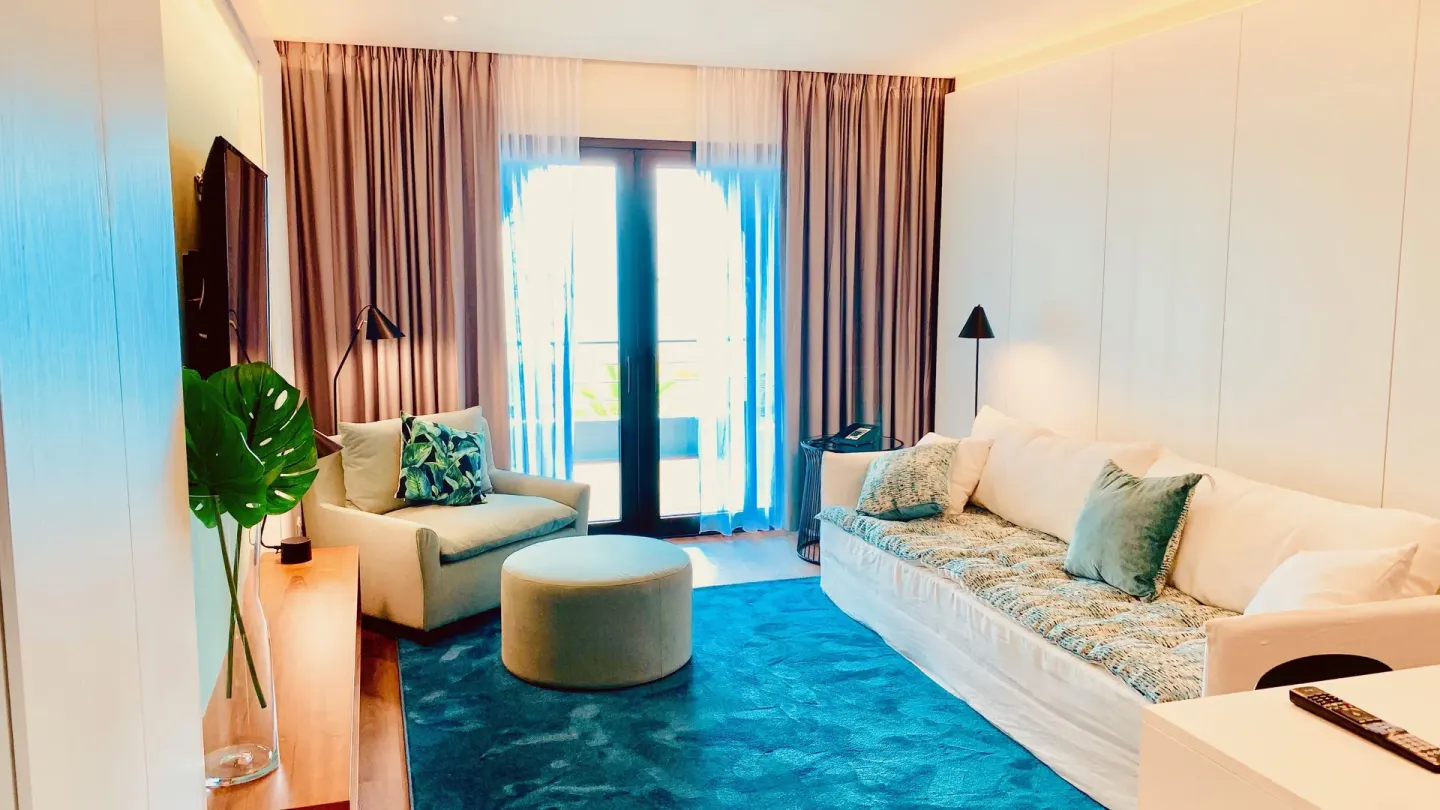 Executive Suite City View sitting area with sofa and balcony doors at Holland House Beach Hotel.
