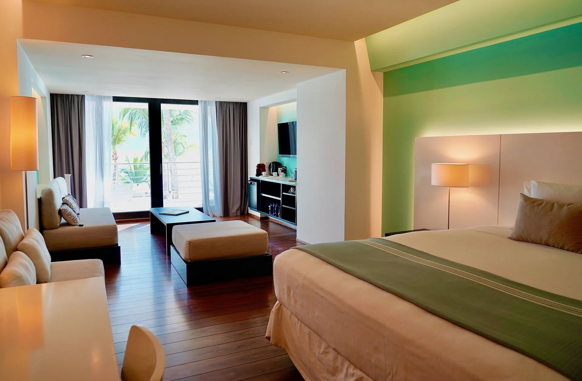 Junior Studio Suite with bed, lounge area and balcony light at Holland House Beach Hotel.