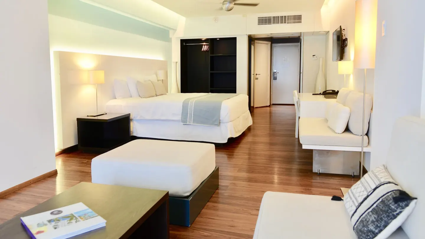 Junior Studio Suite with king bed, sofa seating and entry area at Holland House Beach Hotel.