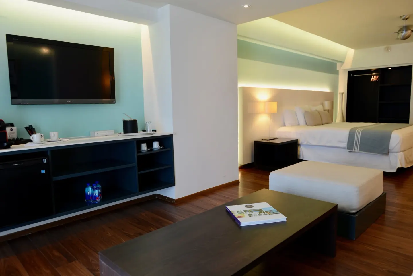 Junior Studio Suite with king bed, TV wall and lounge table at Holland House Beach Hotel.