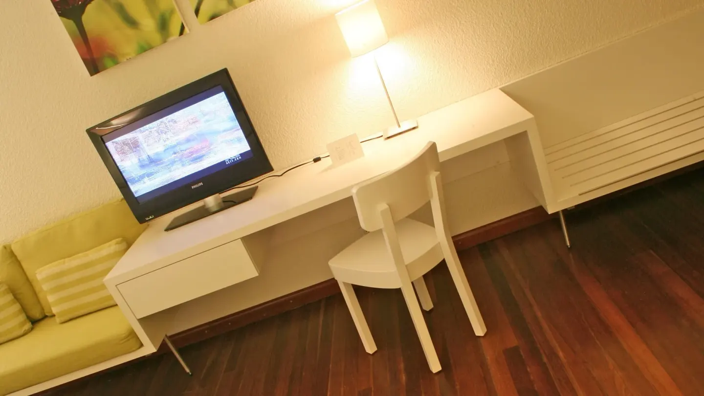 Superior Room City View desk, chair, TV, and sofa at Holland House Beach Hotel.