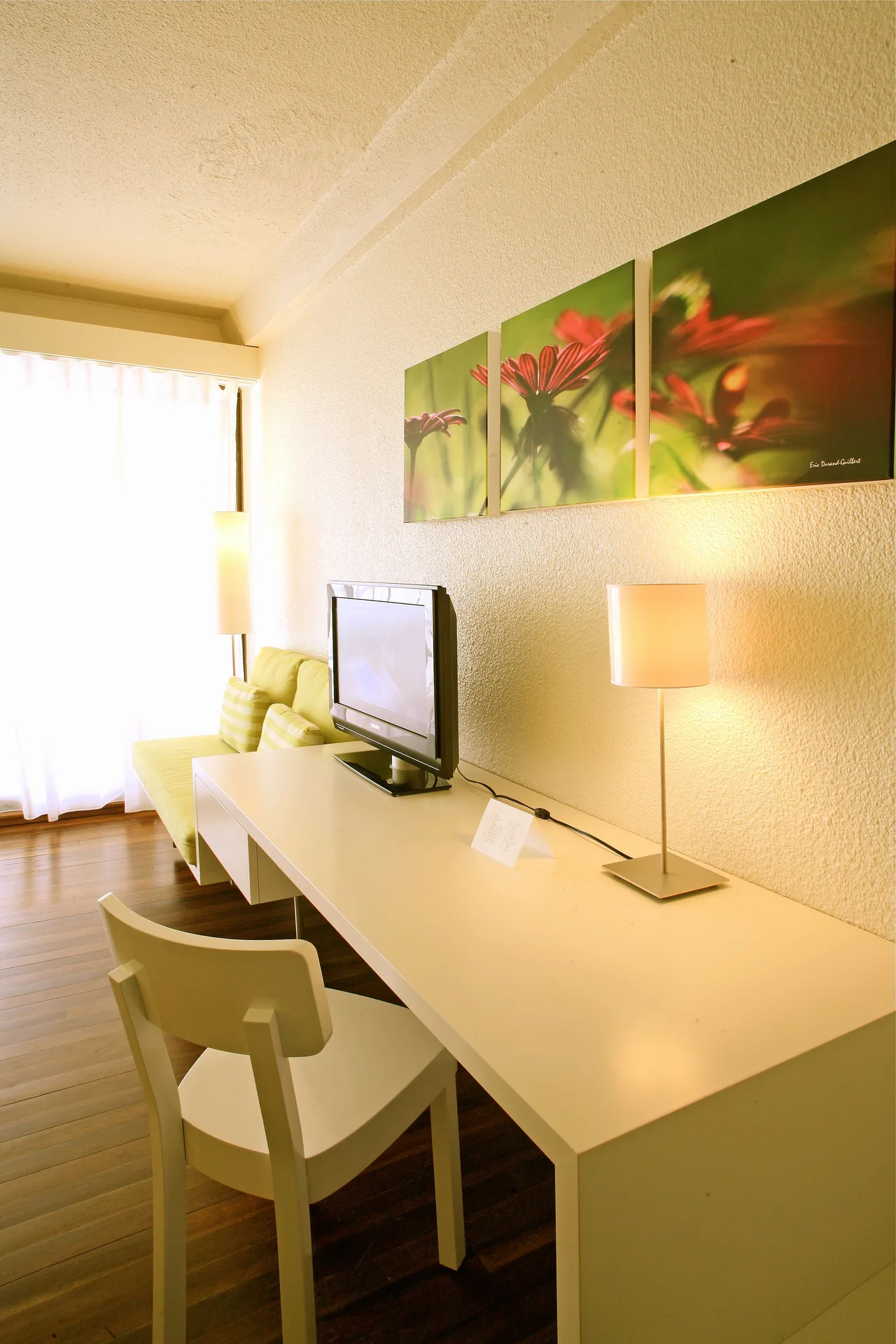 Superior Room City View desk, TV, sofa, and floral wall art at Holland House Beach Hotel.