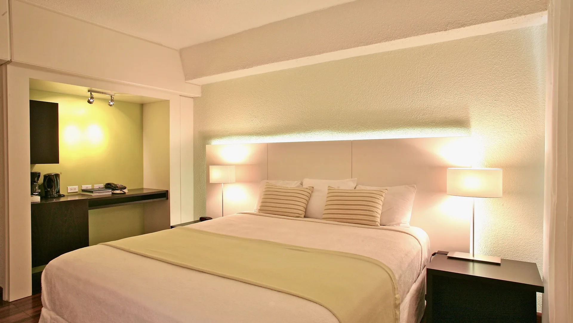 Superior Room City View bed with lit bedside lamps at Holland House Beach Hotel.