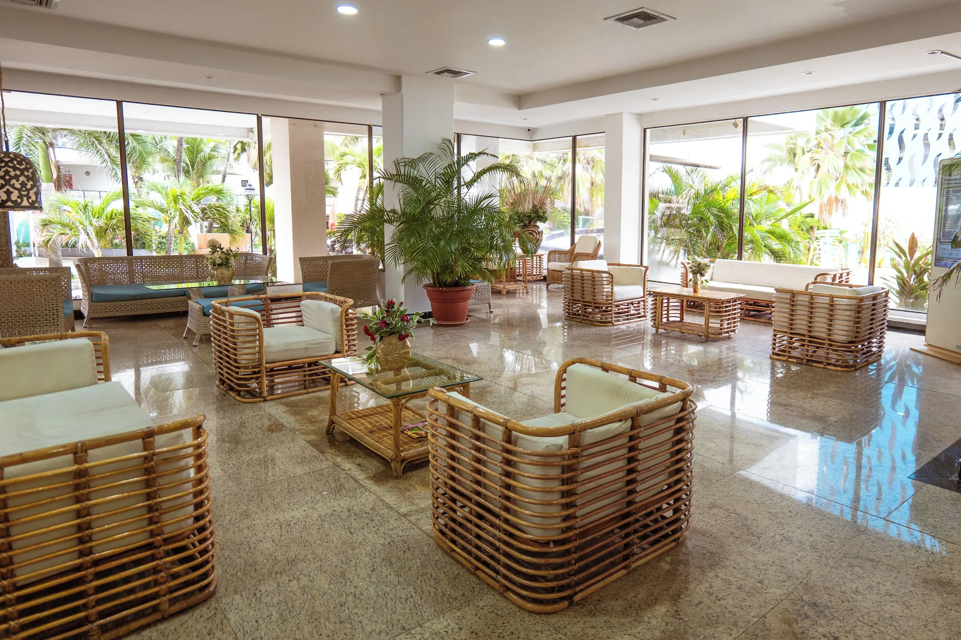 Bright lobby lounge with rattan chairs and large garden-facing windows at Hotel Arena Blanca.