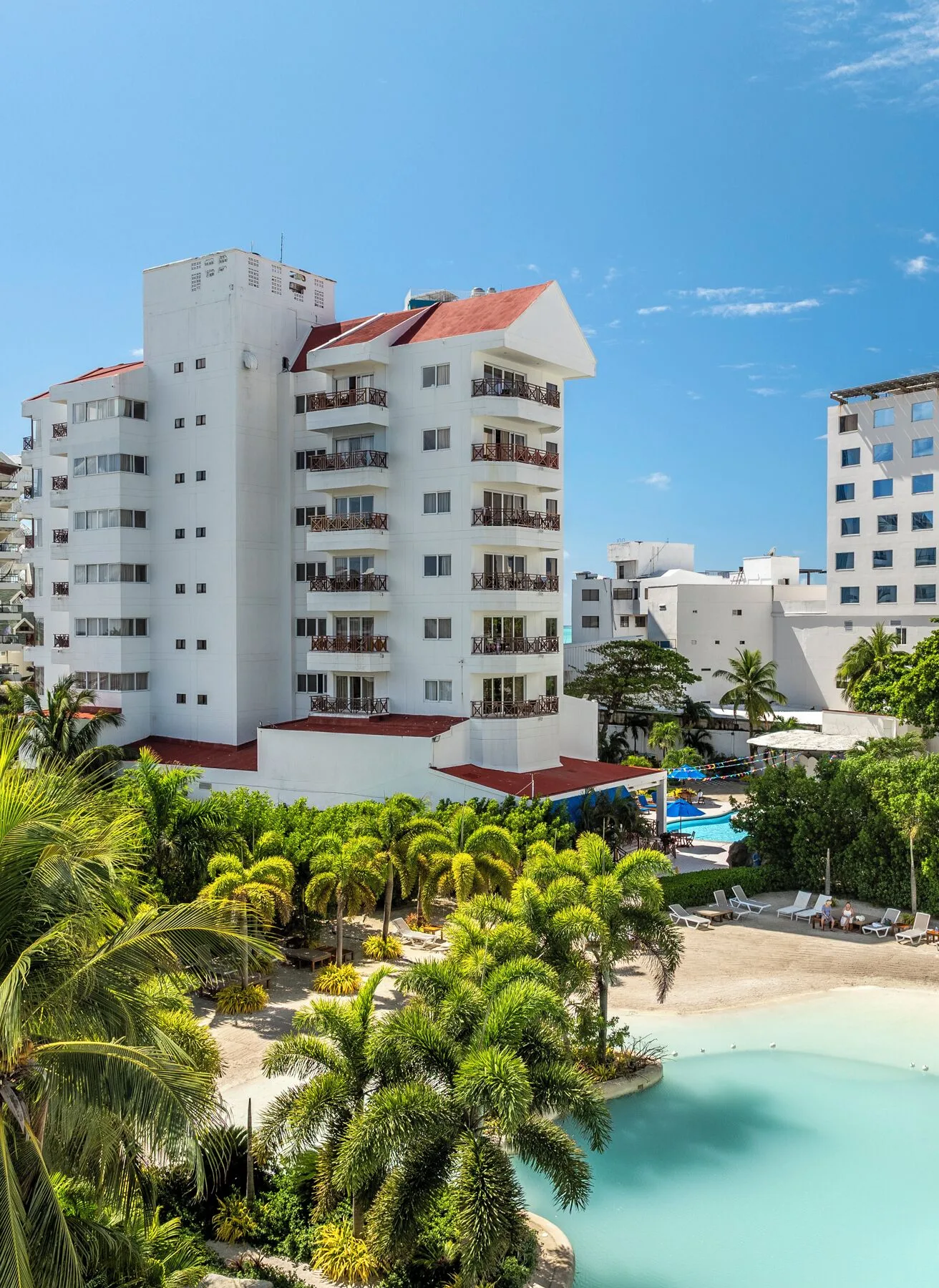 White hotel building above palms and pool at Hotel Arena Blanca.