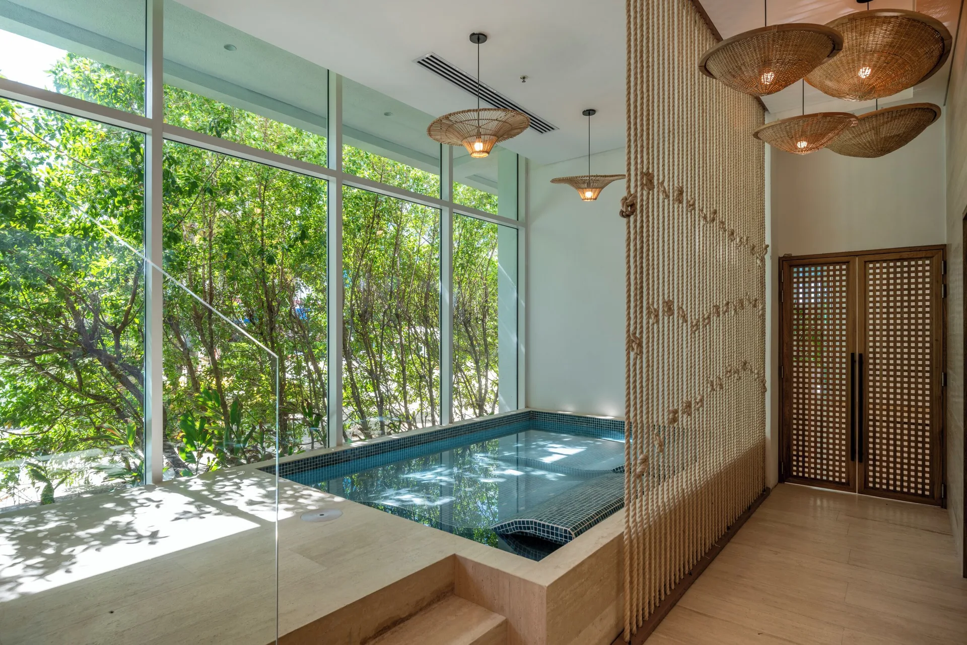 Indoor spa pool with large windows and woven pendant lights at Hotel Arena Blanca.