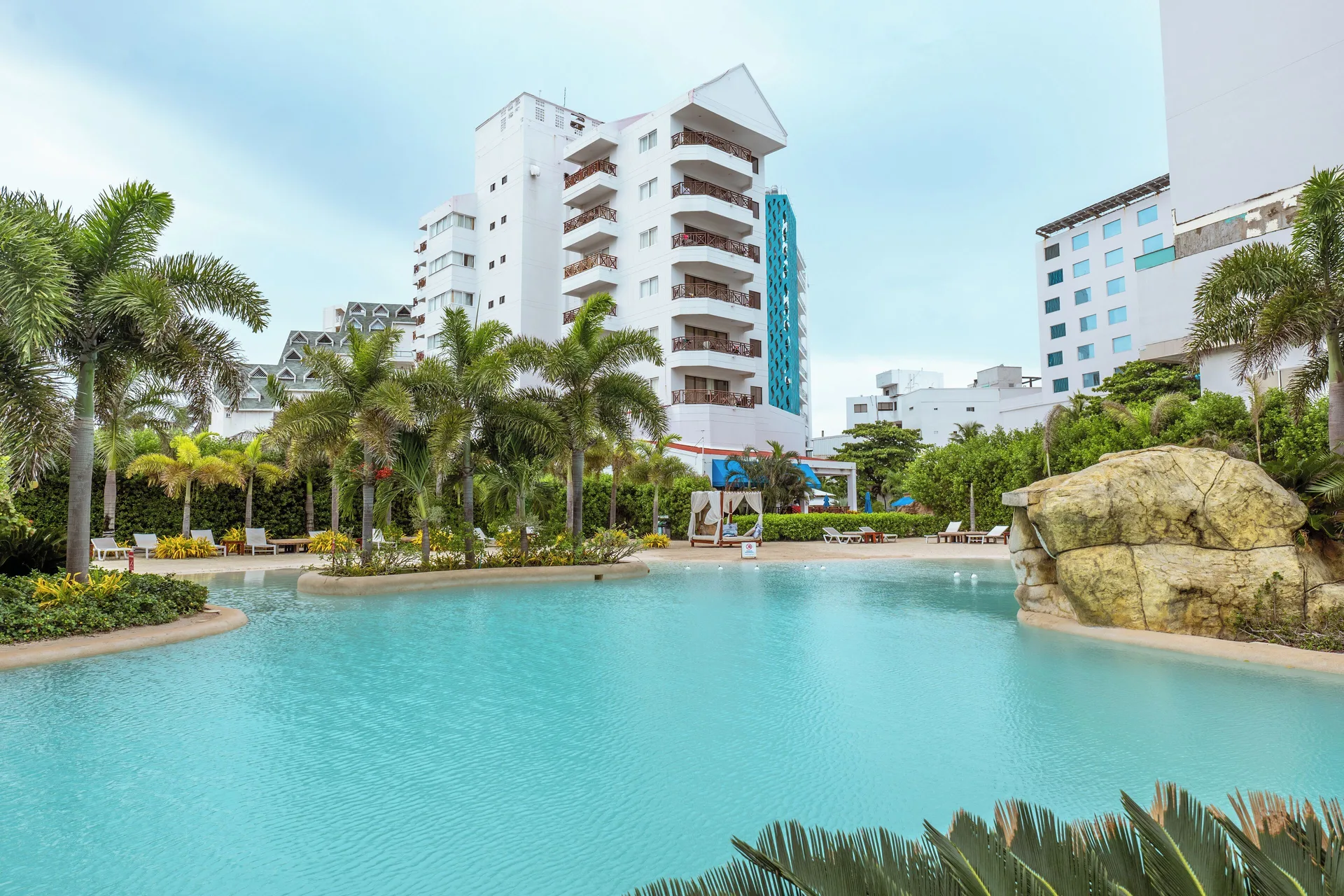 Lagoon-style pool with palms and hotel buildings at Hotel Arena Blanca.