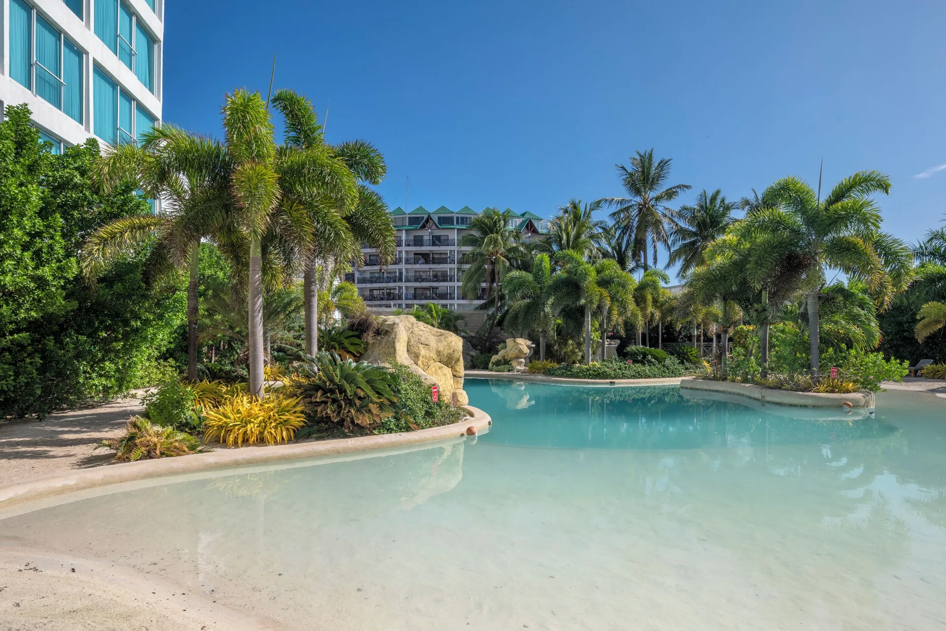 Lagoon-style pool with palms and resort buildings at Hotel Arena Blanca.