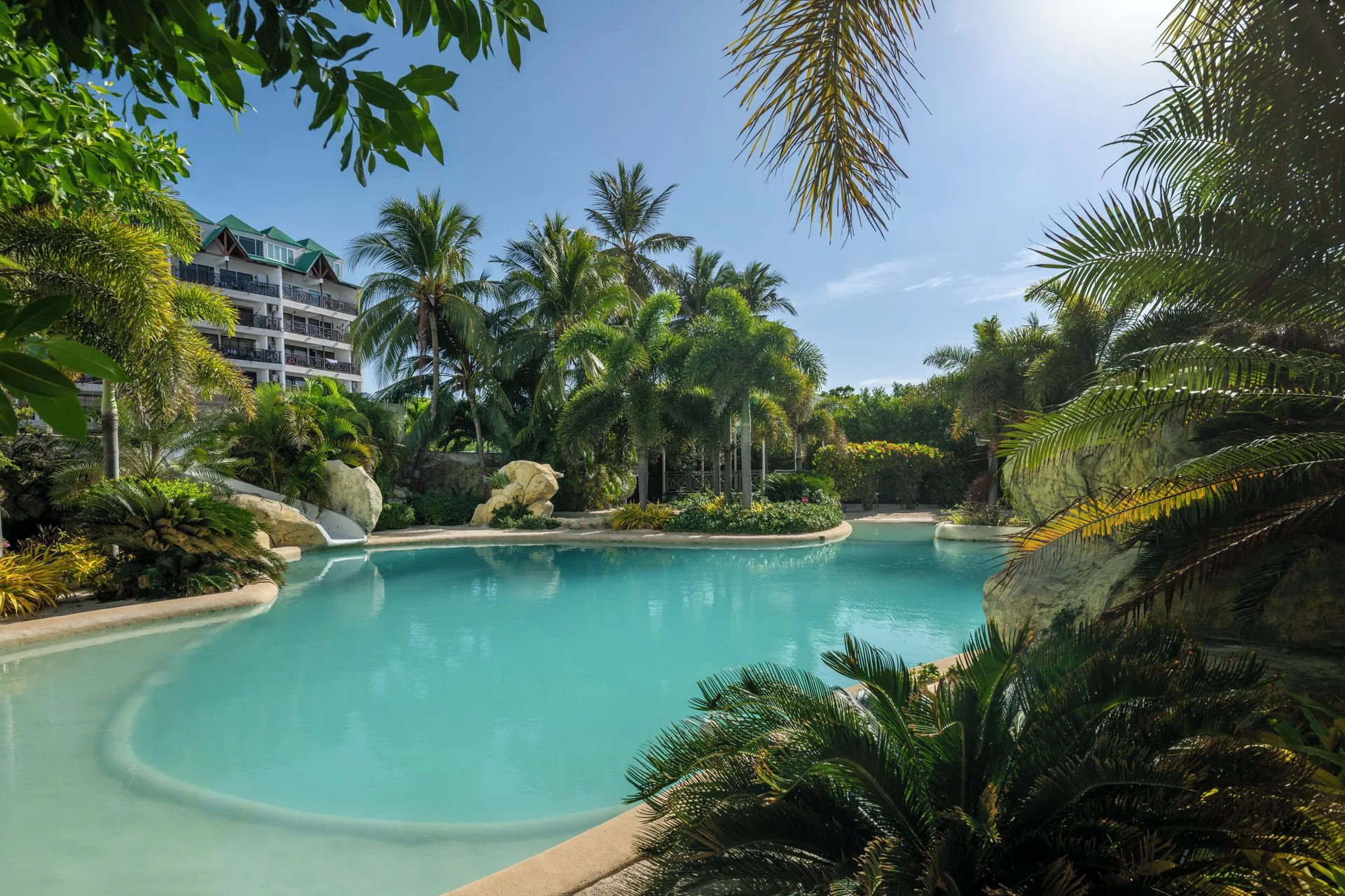 Lagoon-style pool surrounded by palms and rocks at Hotel Arena Blanca.