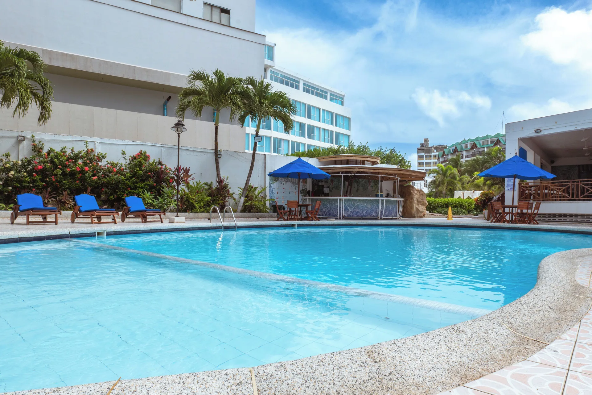 Outdoor swimming pool with blue loungers and umbrellas at Hotel Arena Blanca.