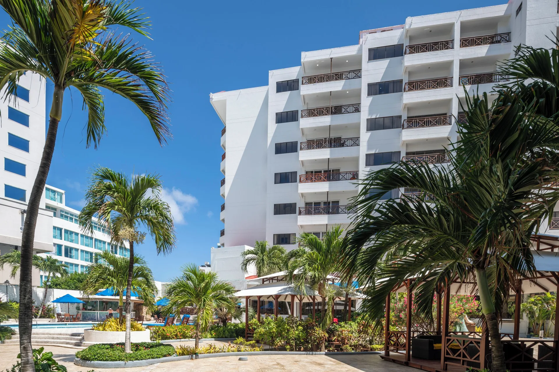 Palm-lined courtyard and white balconies beside the pool at Hotel Arena Blanca.