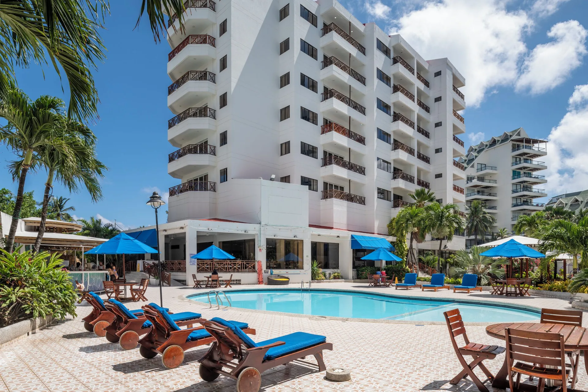 Pool deck with blue loungers and white guest tower at Hotel Arena Blanca.