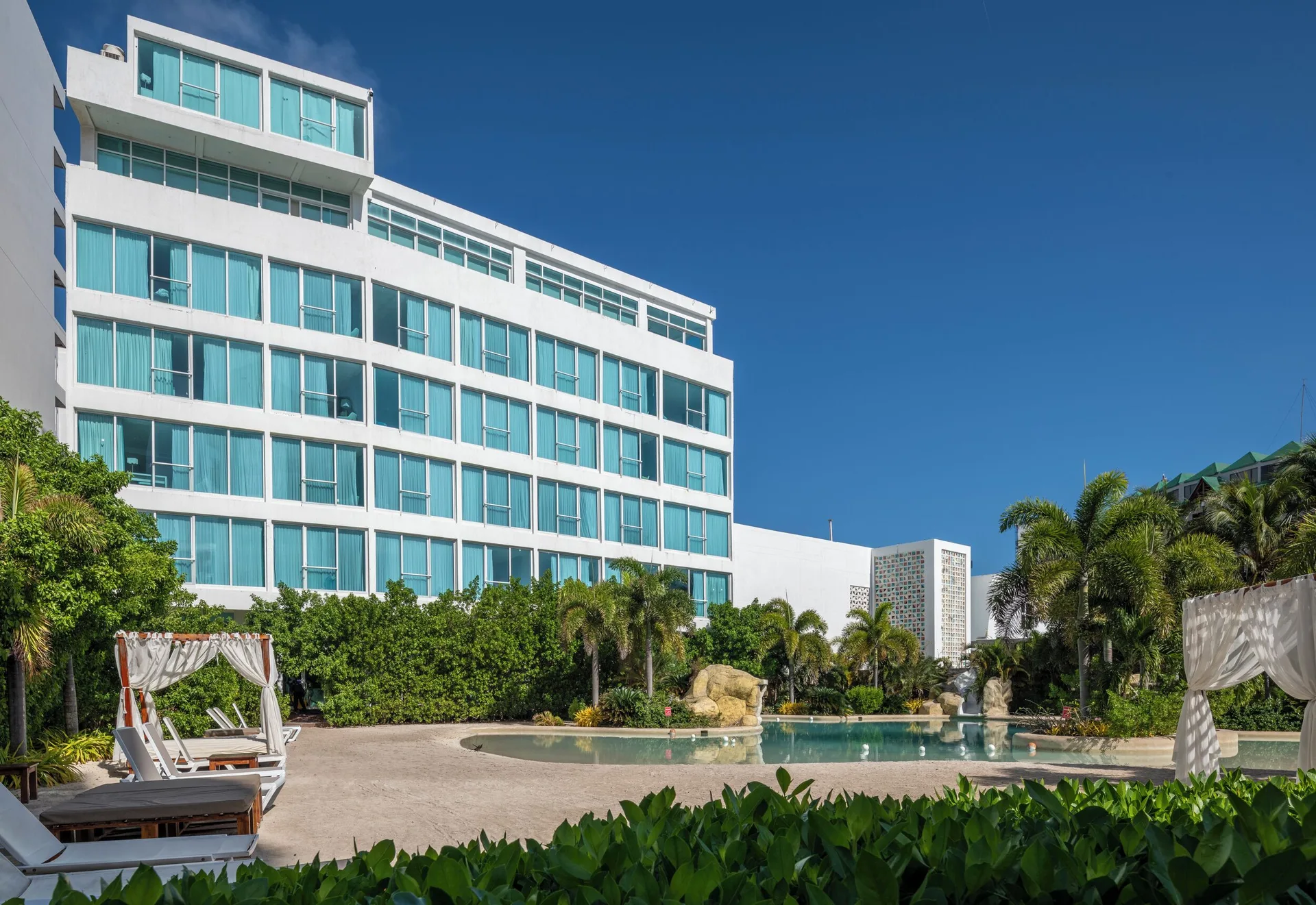 White hotel building with turquoise windows overlooking the pool at Hotel Arena Blanca.