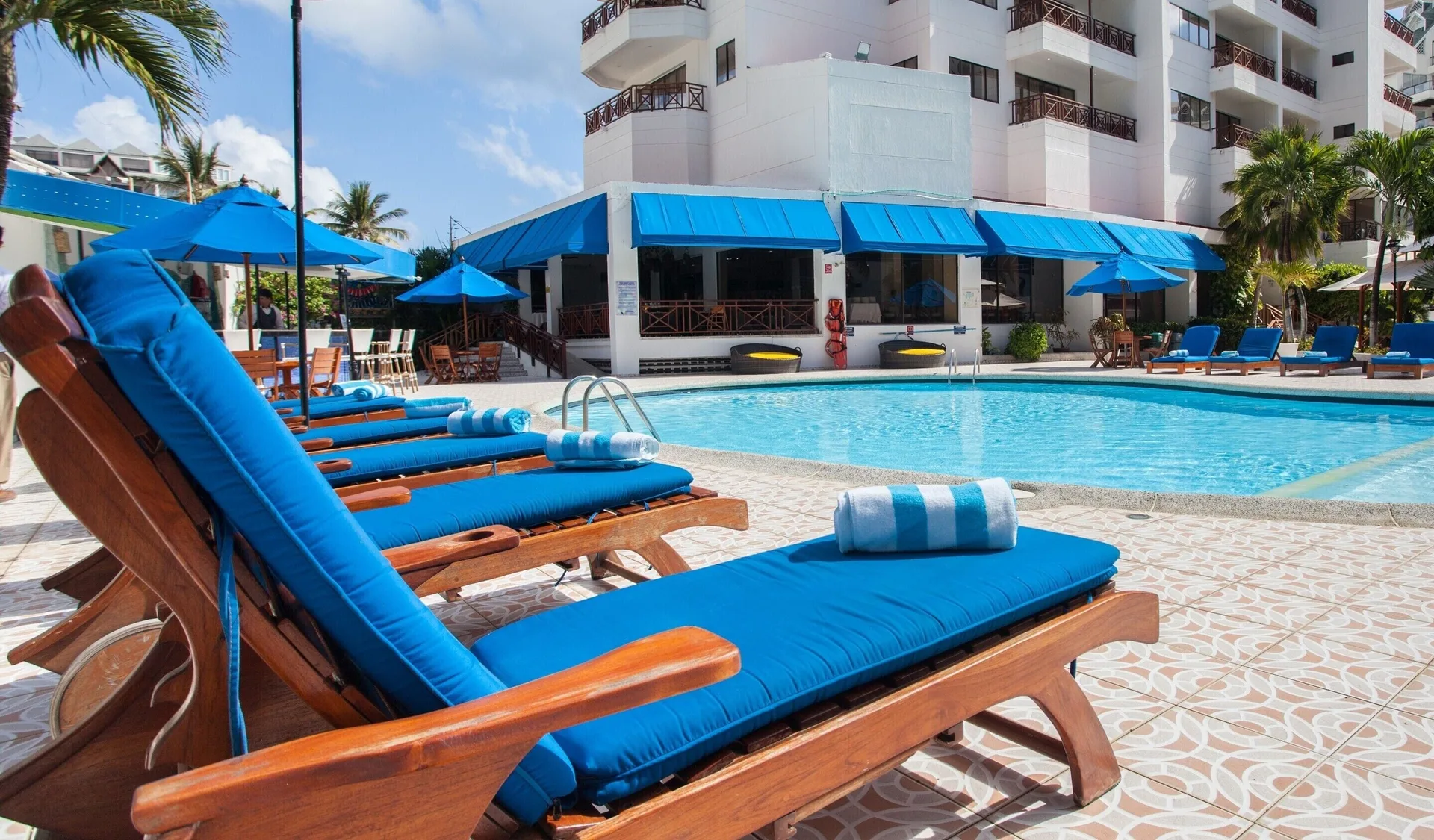 Blue cushioned sun loungers with towels beside the pool at Hotel Arena Blanca.