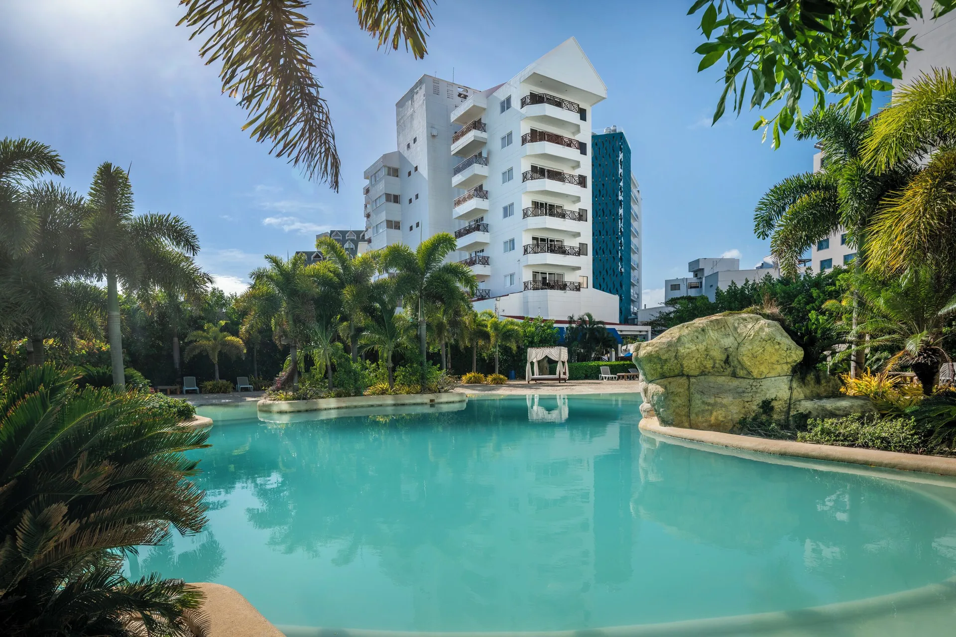 Curved pool with palms and a white tower building at Hotel Arena Blanca.
