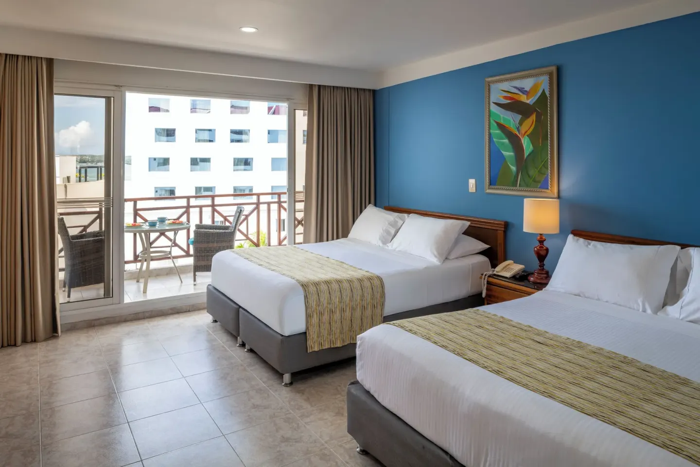 Standard Quadruple Room with two double beds and balcony doors at Hotel Arena Blanca.