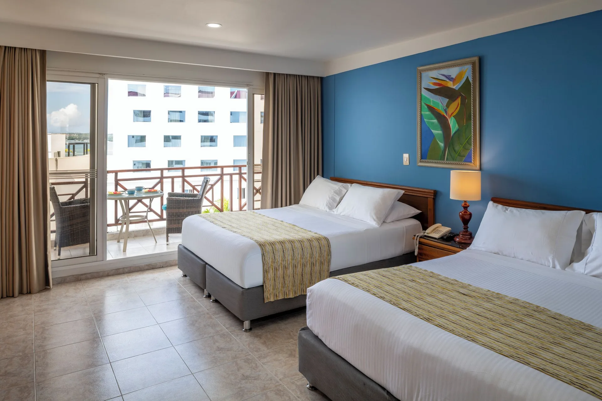 Standard Quadruple Room with two double beds and balcony doors at Hotel Arena Blanca.