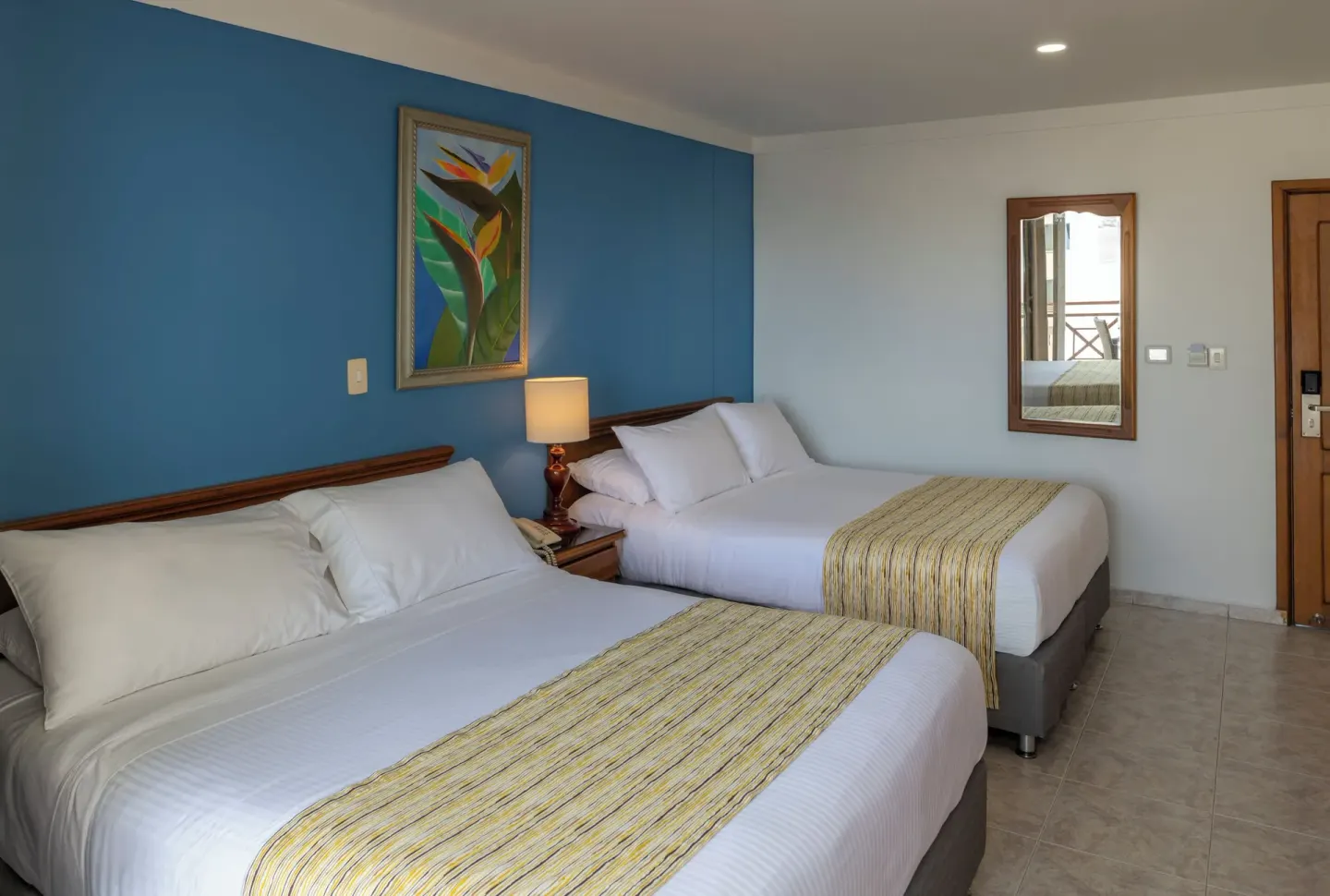 Standard Quadruple Room with two double beds, blue wall, and entry door at Hotel Arena Blanca.