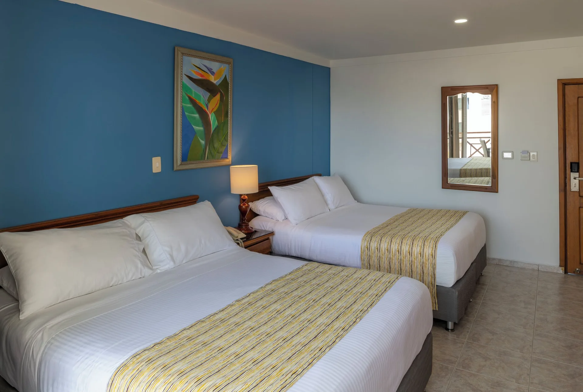 Standard Quadruple Room with two double beds, blue wall, and entry door at Hotel Arena Blanca.