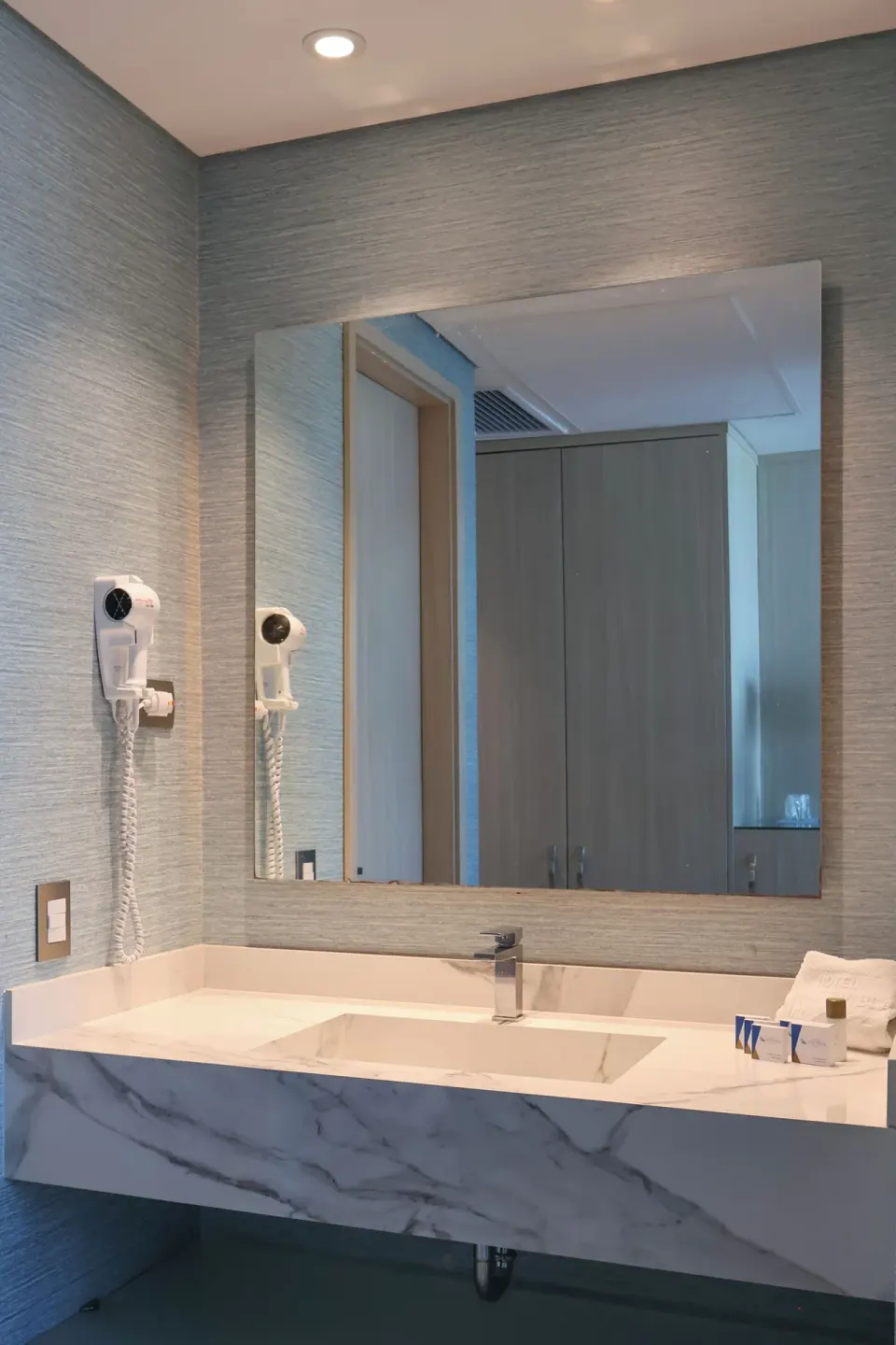 Superior Room bathroom vanity with mirror, sink, hair dryer, and towels at Hotel Arena Blanca.