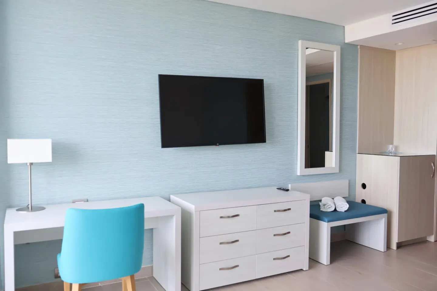 Superior Room TV wall with desk, chair, dresser, mirror, and bench at Hotel Arena Blanca.