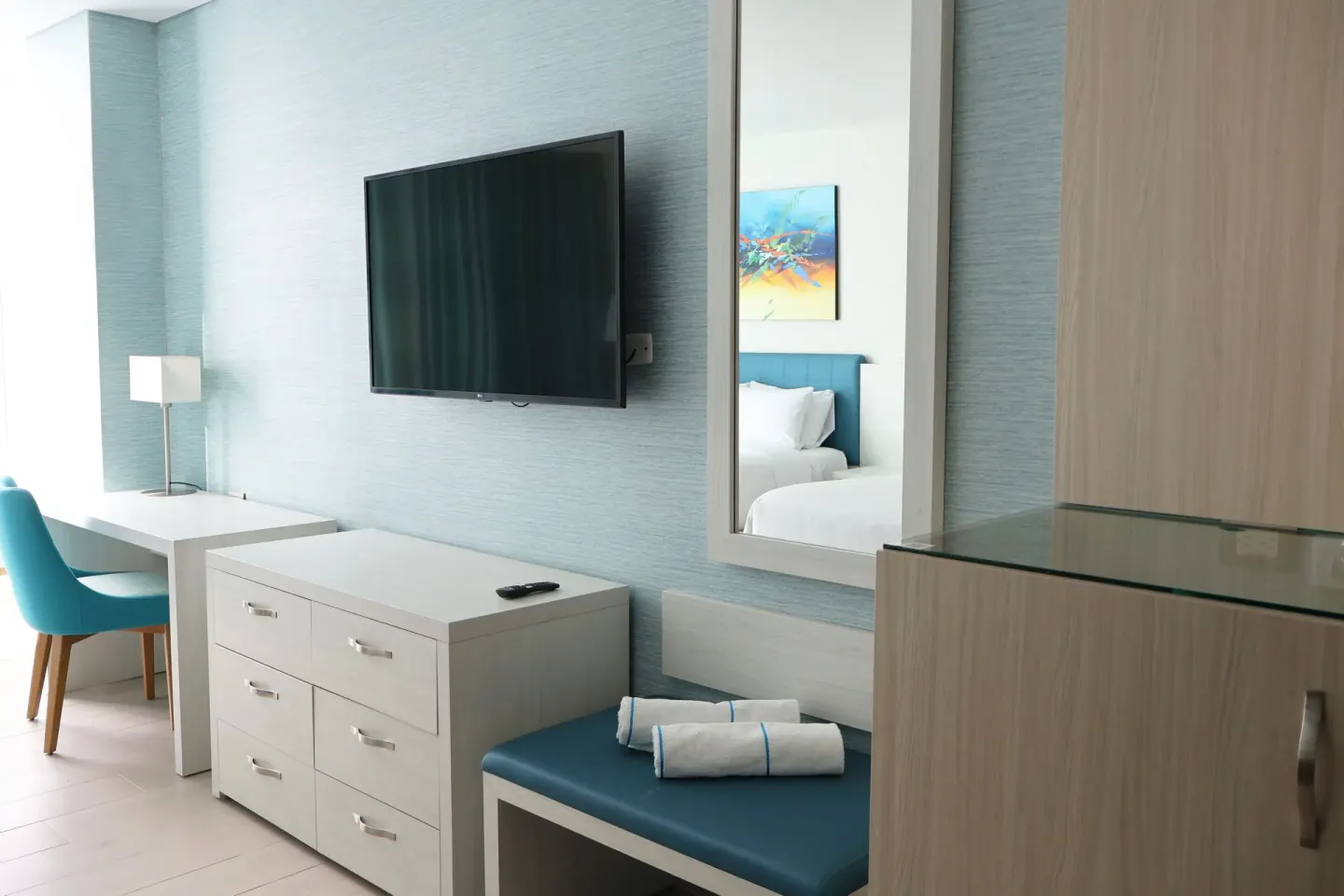 Superior Room dresser, TV, mirror, bench, and desk at Hotel Arena Blanca.