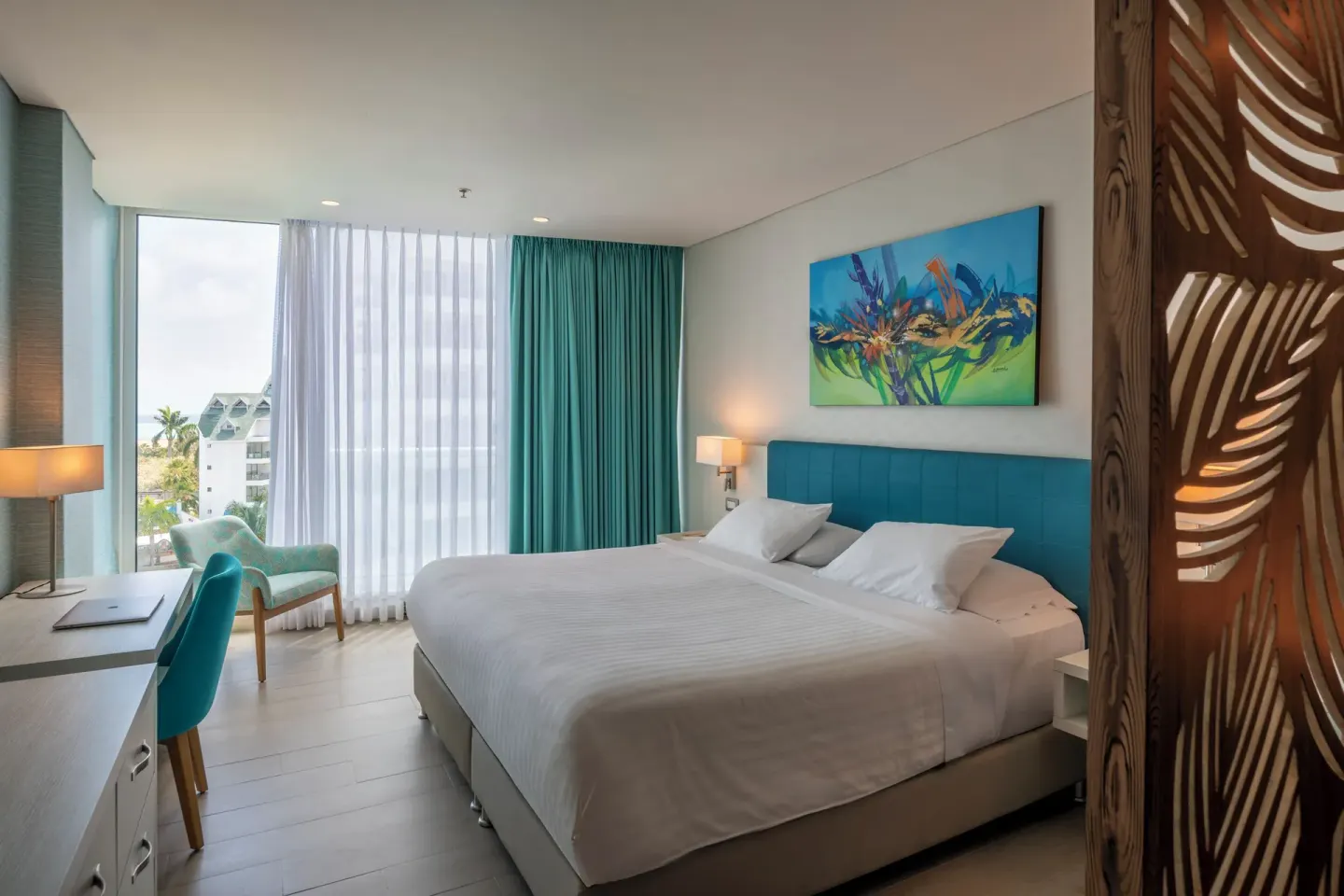 Superior Room king bed, desk, chair, window, and teal curtains at Hotel Arena Blanca.