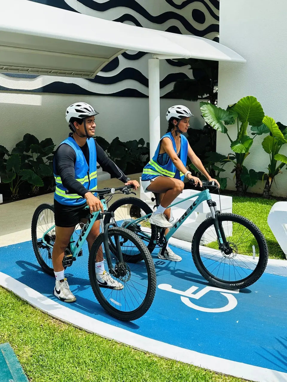 Two cyclists with helmets on a marked path at Hotel Azul Ixtapa Grand Resort Spa.