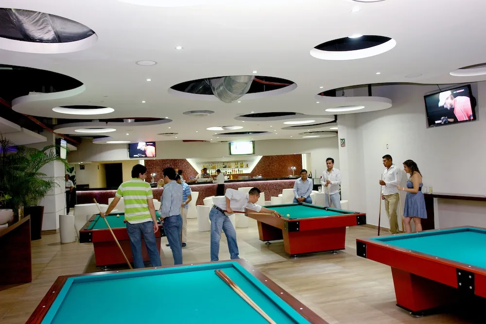 Game room with billiards tables and bar seating at Hotel Azul Ixtapa Grand Resort Spa.