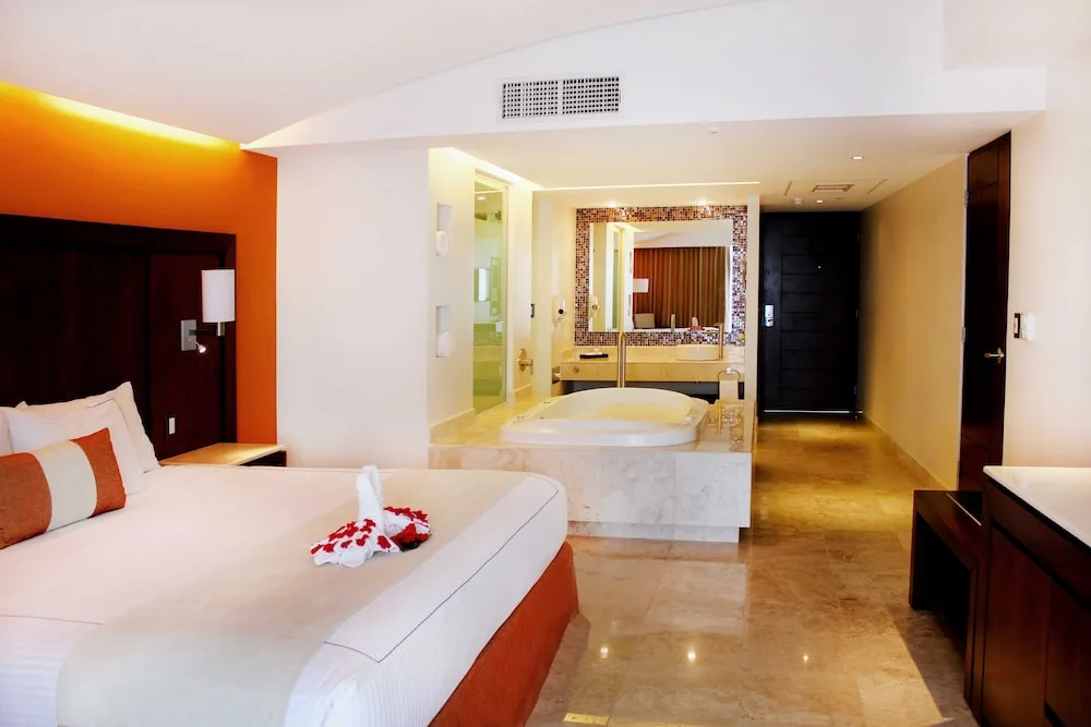 King guest room with orange accent wall and jetted tub at Hotel Azul Ixtapa Grand Resort Spa.