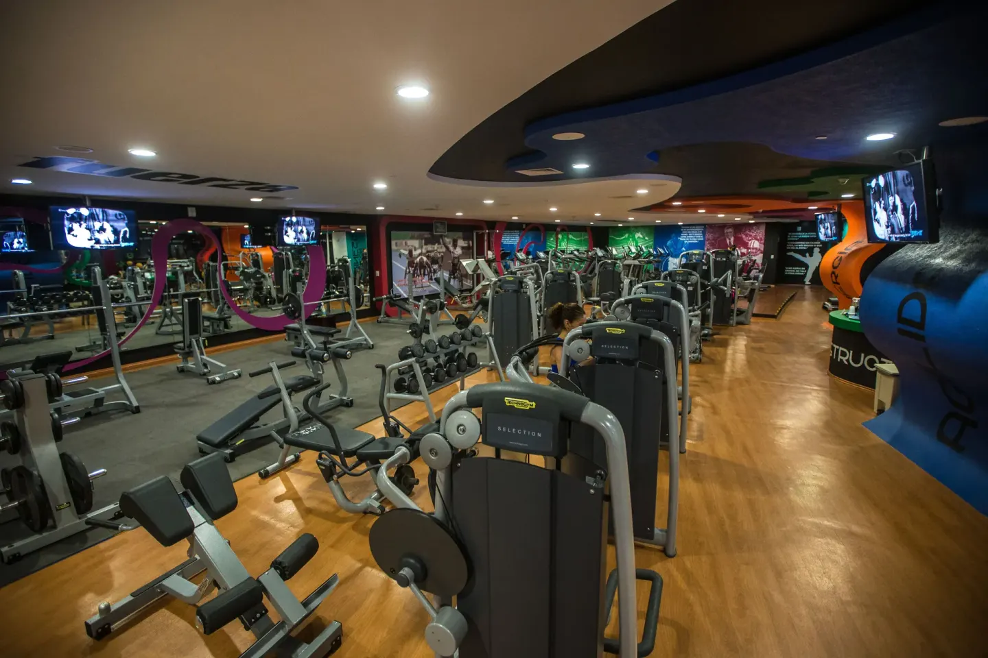 Gym with strength machines, mirrors and wall-mounted screens at Hotel Azul Ixtapa Grand Resort Spa.
