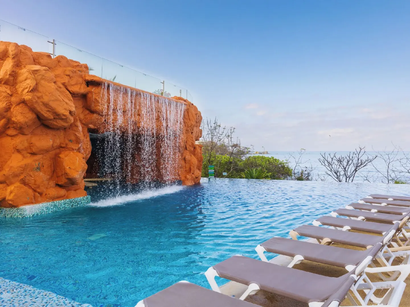 Infinity pool with rock waterfall and ocean beyond at Hotel Azul Ixtapa Grand Resort Spa.