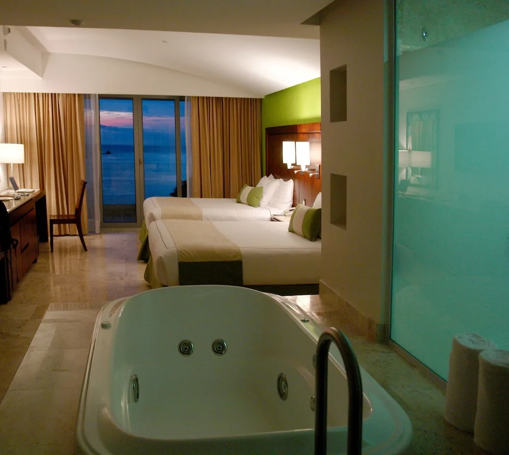 Suite with two beds, jetted tub, and ocean-view balcony at Hotel Azul Ixtapa Grand Resort Spa.