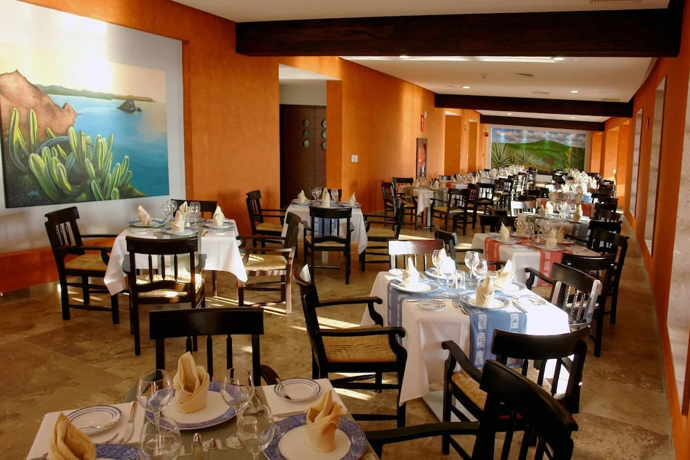 Mexican-style dining room with orange walls and set tables at Hotel Azul Ixtapa Grand Resort Spa.