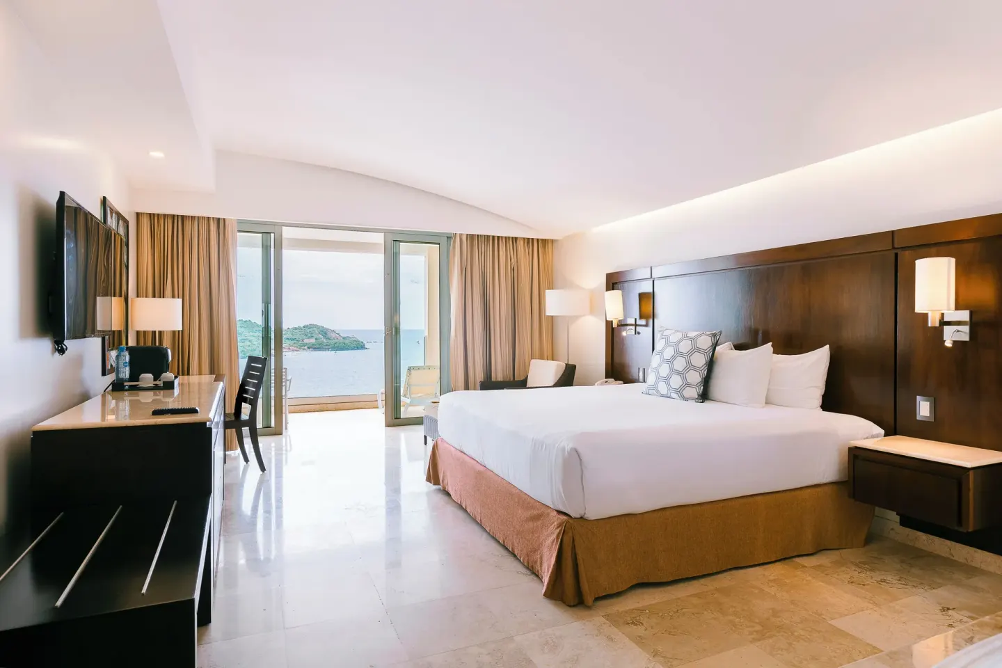 Luxury Room king bed, desk and balcony with ocean view at Hotel Azul Ixtapa Grand Resort Spa.