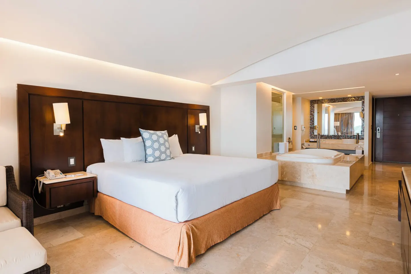 Luxury Room king bed with bedside lamps and open bathing area at Hotel Azul Ixtapa Grand Resort Spa.