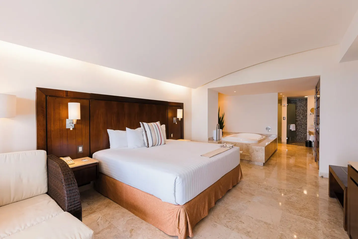 Master Suite bedroom with king bed and open whirlpool bath at Hotel Azul Ixtapa Grand Resort Spa.