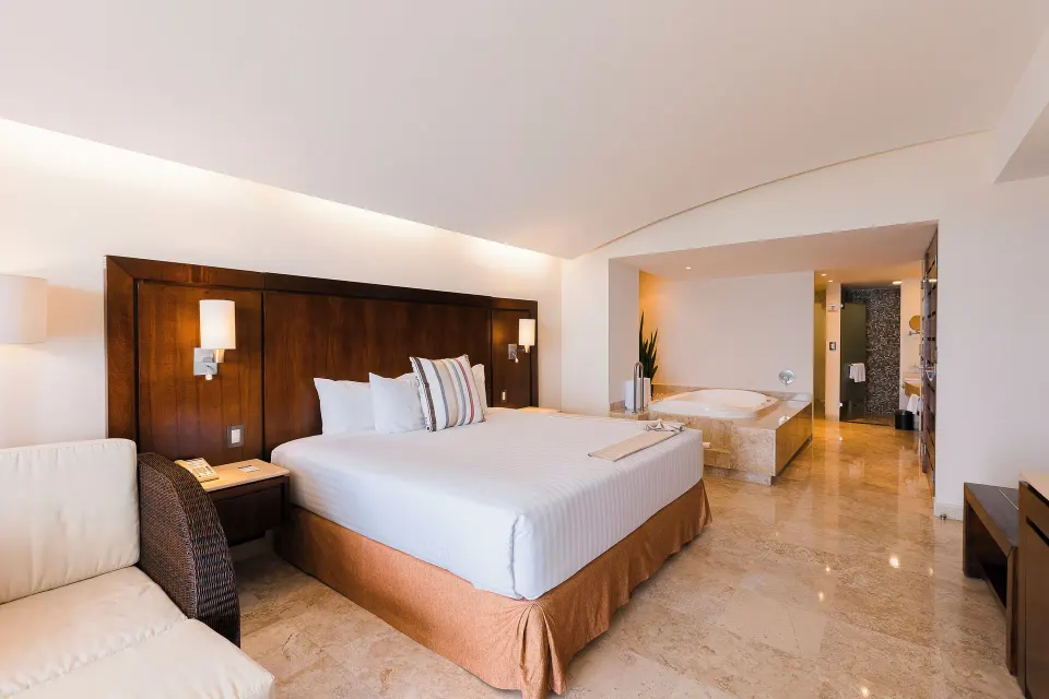 Master Suite bedroom with king bed and open whirlpool bath at Hotel Azul Ixtapa Grand Resort Spa.