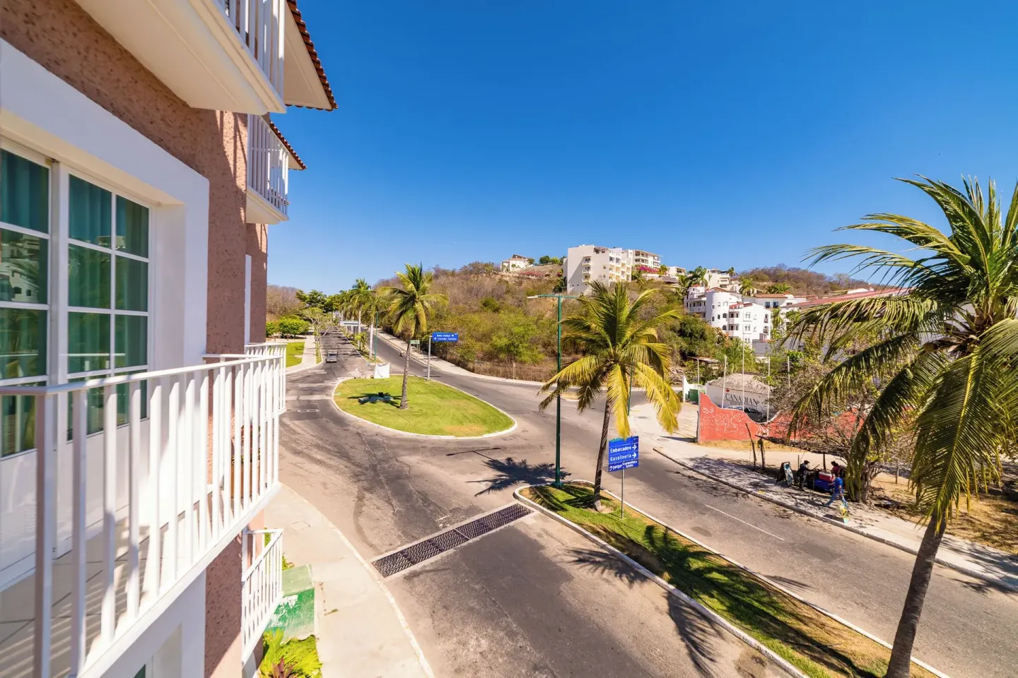 Balcony view of a palm-lined road near Hotel Castillo Huatulco & Beach Club.