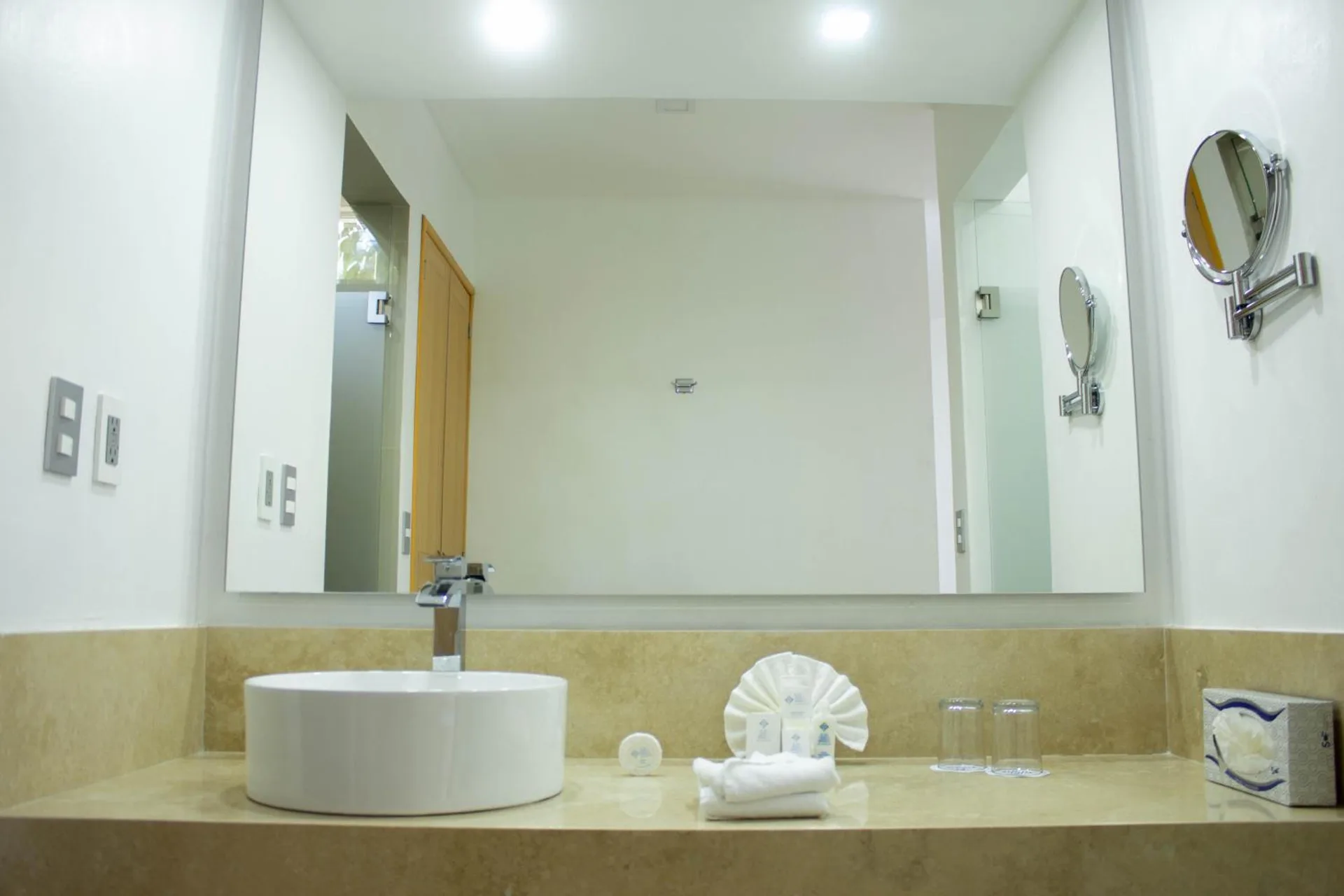 Bathroom vanity with round vessel sink and large mirror at Hotel Castillo Huatulco & Beach Club.