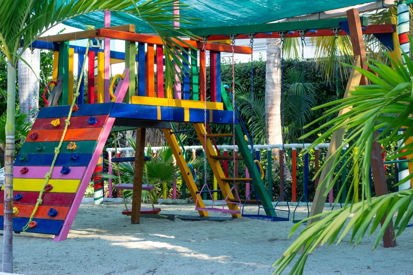 Colorful children’s play structure with swings and climbing wall at Hotel Castillo Huatulco & Beach Club.