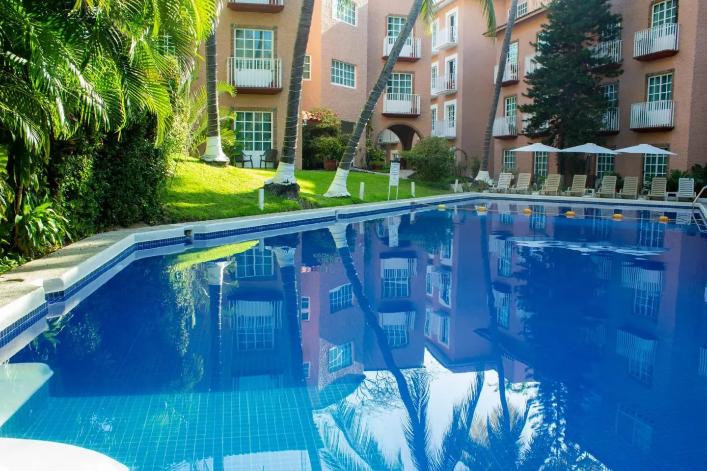 Courtyard pool surrounded by palms at Hotel Castillo Huatulco & Beach Club.
