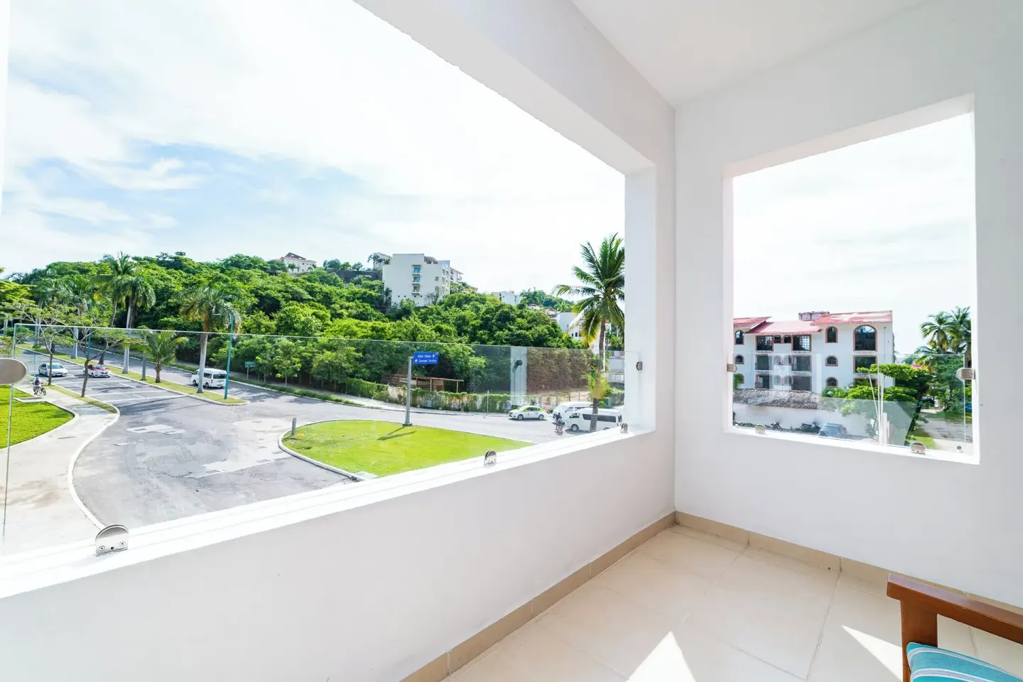 Covered balcony at Hotel Castillo Huatulco & Beach Club overlooking road, greenery, and nearby buildings.