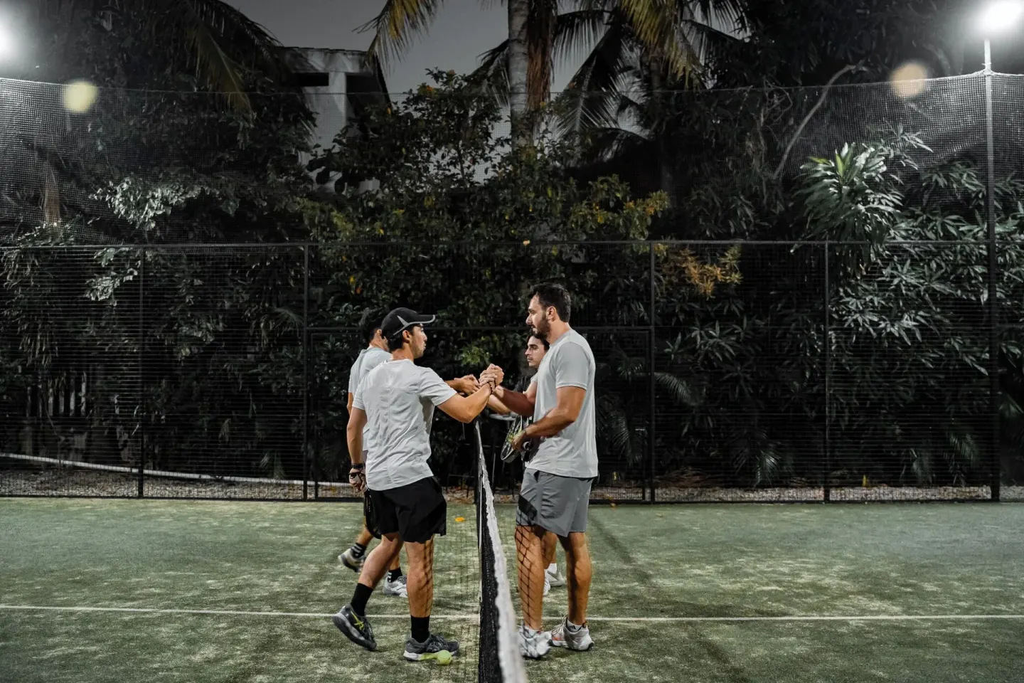 Players meet at the net on a lighted tennis court at Hotel Castillo Huatulco & Beach Club.