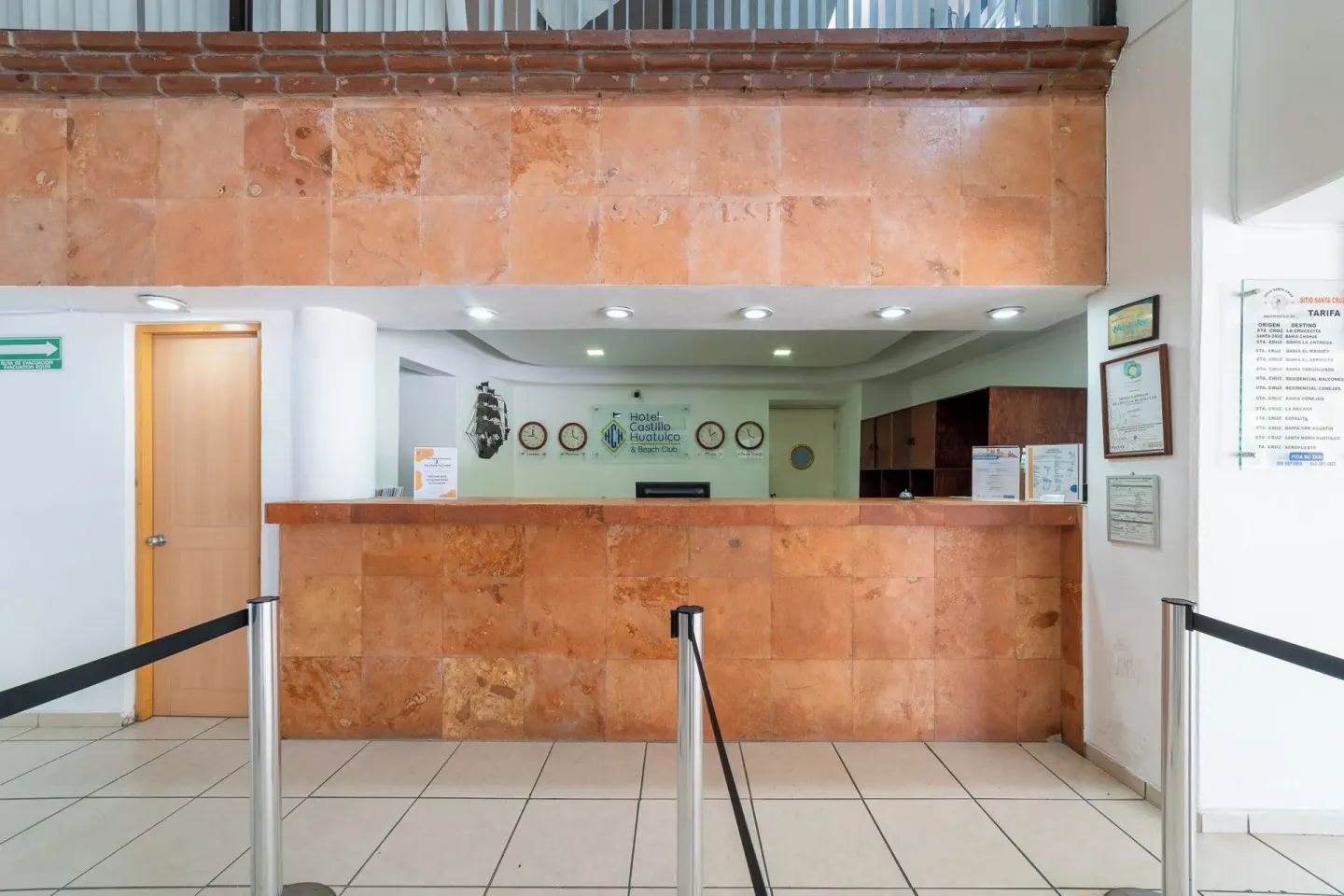 Front desk with stone counter and queue barriers at Hotel Castillo Huatulco & Beach Club.