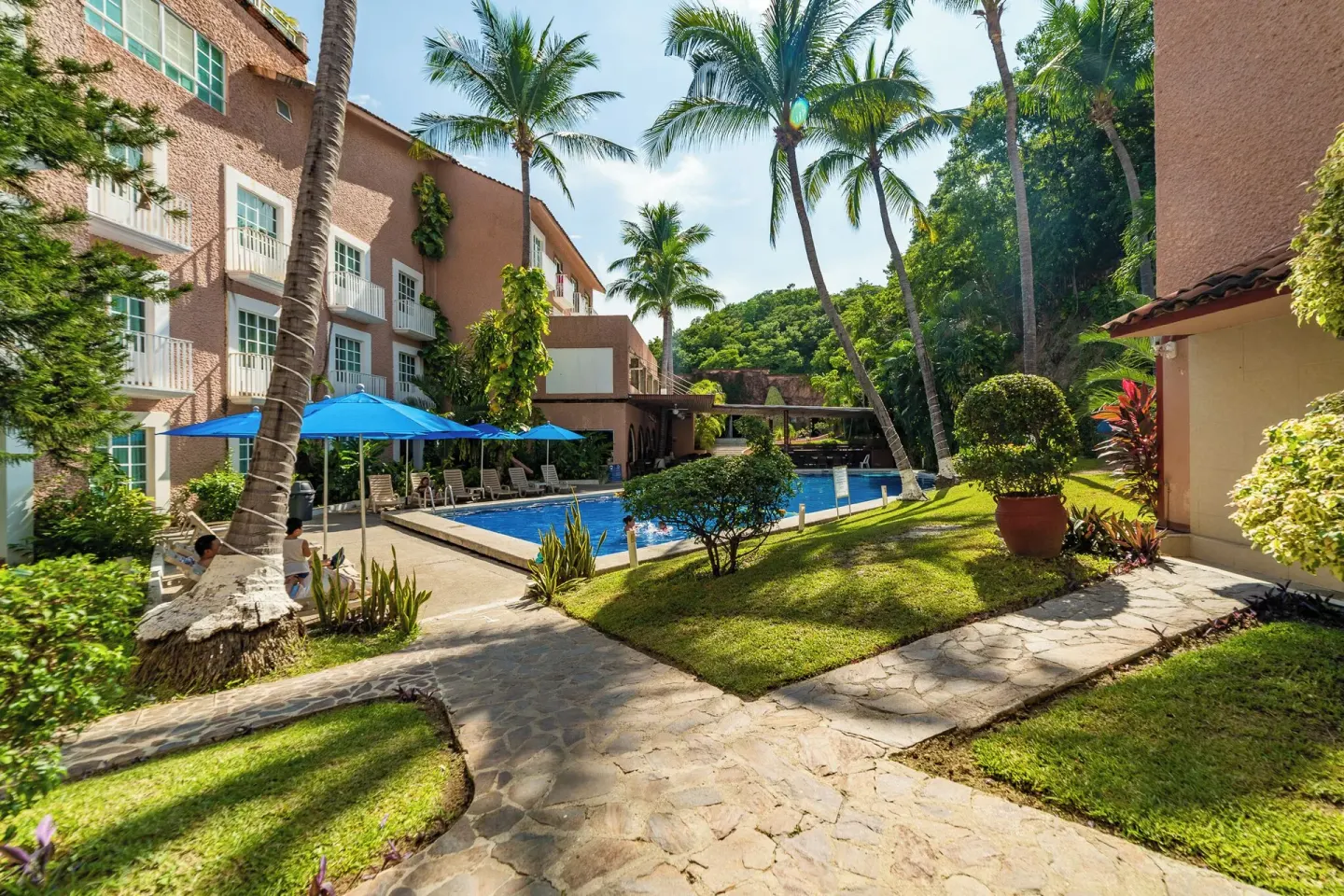 Garden walkway and pool courtyard at Hotel Castillo Huatulco & Beach Club.