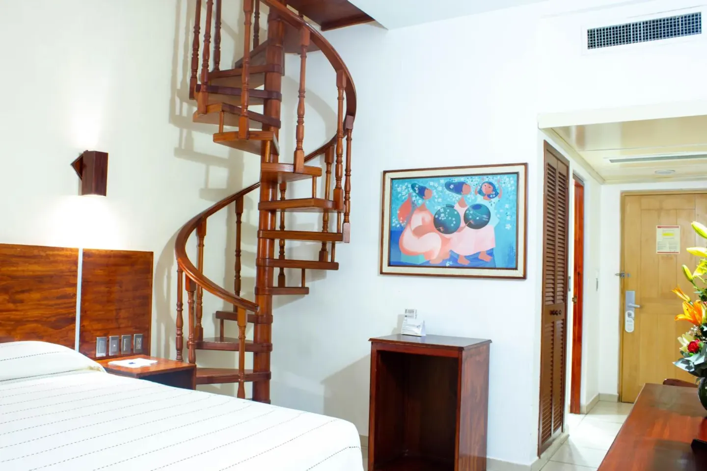 Guest room with a bed and spiral staircase at Hotel Castillo Huatulco & Beach Club.