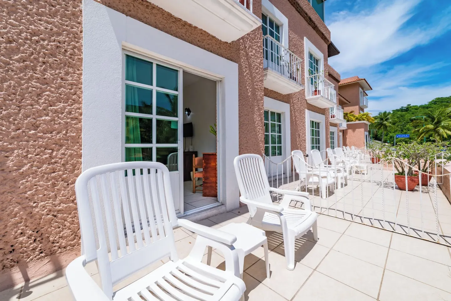Terrace outside guest rooms with white chairs at Hotel Castillo Huatulco & Beach Club.