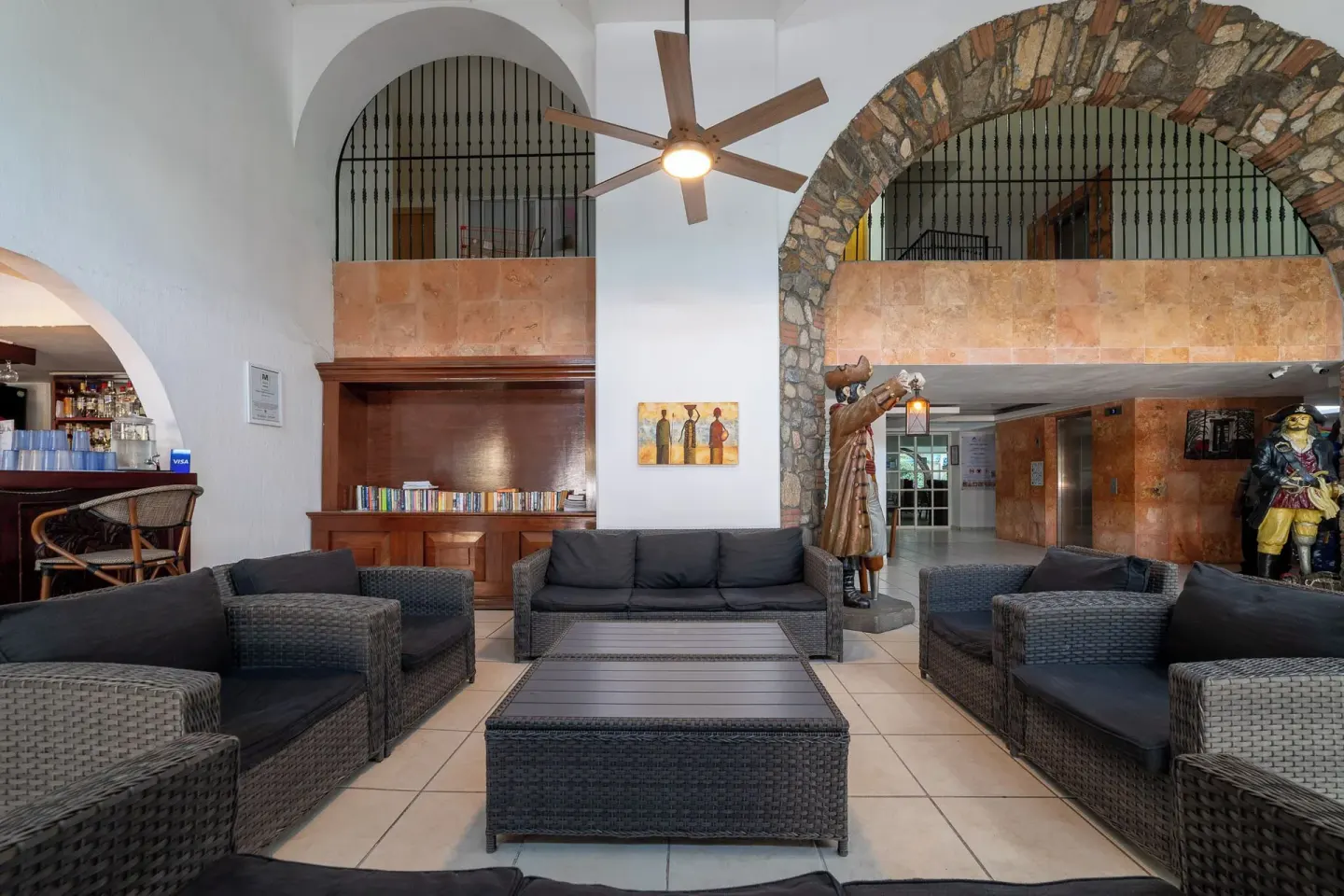 Lobby seating with wicker sofas, arches, and pirate figures at Hotel Castillo Huatulco & Beach Club.
